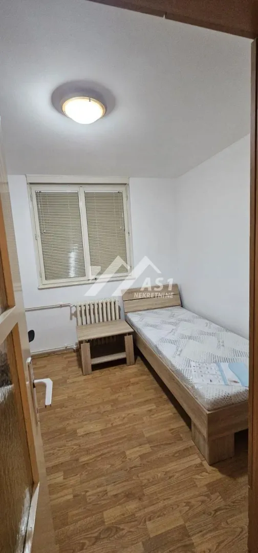 Manja spavaća soba sa krevetom i prozorom.