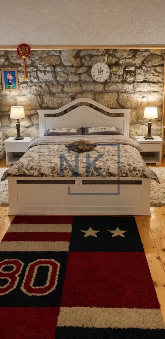 Bedroom with a double bed, nightstands, and a stone wall.