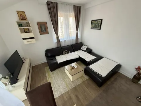 Dnevna soba sa crnom ugaonom garniturom, televizorom i prozorom. - image 2