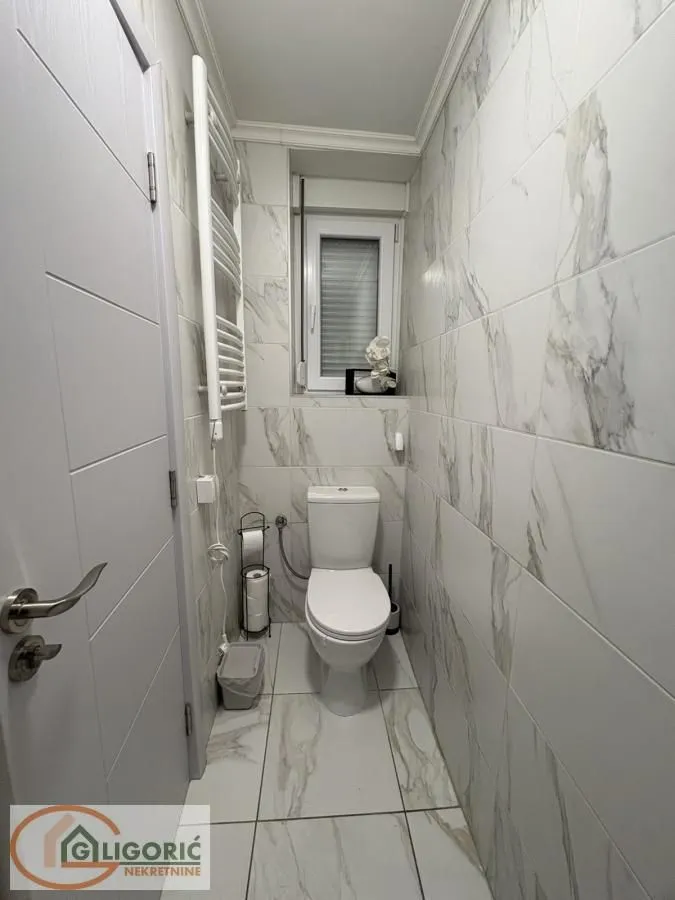 Small bathroom tiled with marble-patterned ceramic tiles.