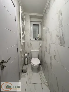 Small bathroom tiled with marble-patterned ceramic tiles. - image 8
