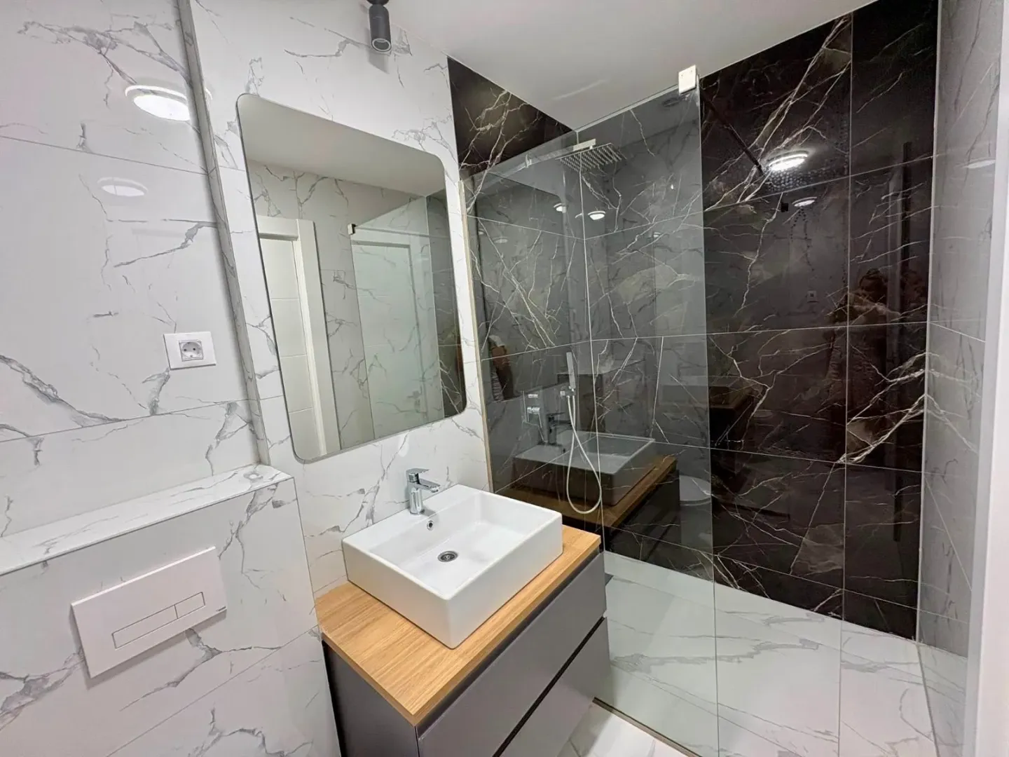 Modern bathroom with a washbasin, mirror, and a tiled walk-in shower.