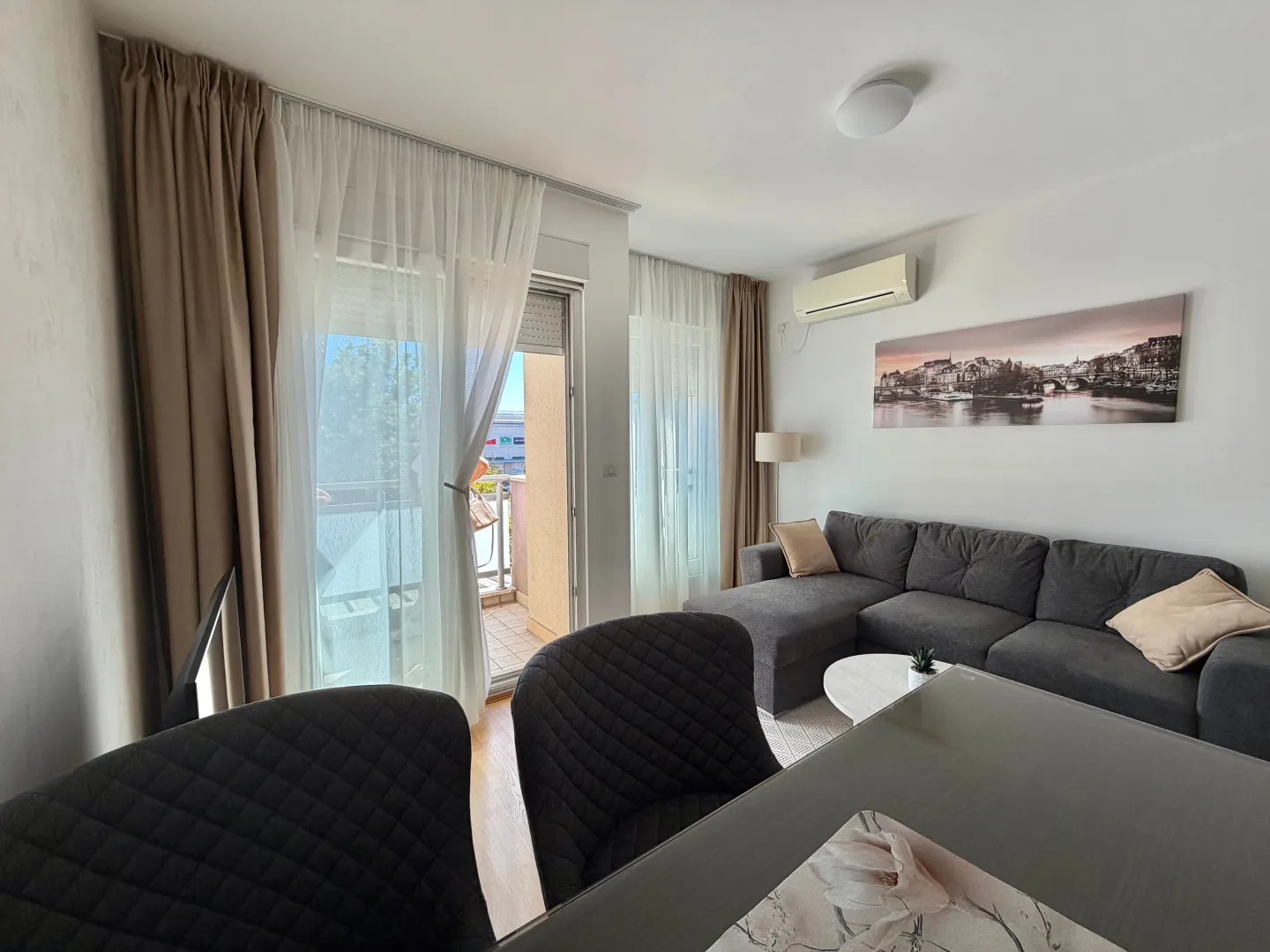 Bright living room with a sofa and dining table, with access to the terrace.