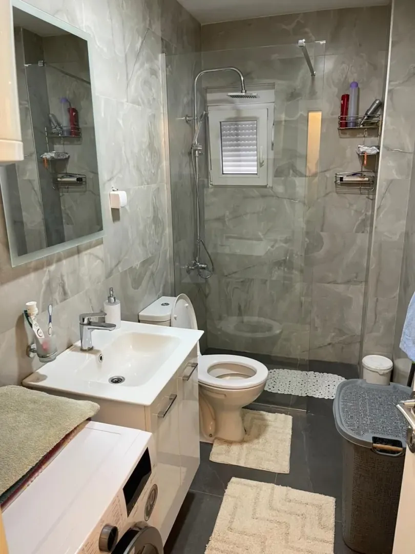 Modern bathroom with a shower cabin, sink, and washing machine.