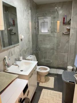 Modern bathroom with a shower cabin, sink, and washing machine. - image 13