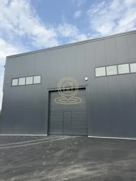 Exterior of an industrial building with a roll-up door and paved yard. - image 6