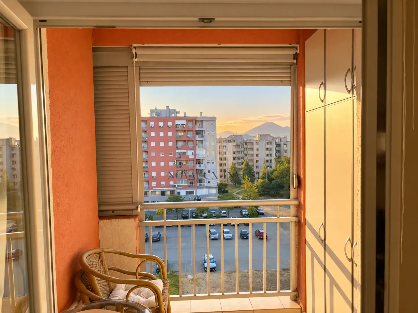 Natkriveni balkon sa ormarićem, garniturom za sjedenje i pogledom na naselje.