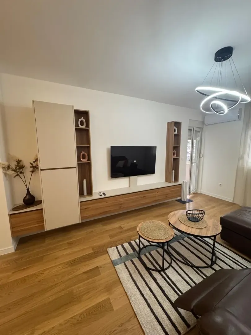 Living room with sofa, TV unit, and modern chandelier.
