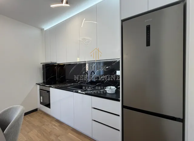 Modern kitchen with white cabinetry, black countertops, and a refrigerator.