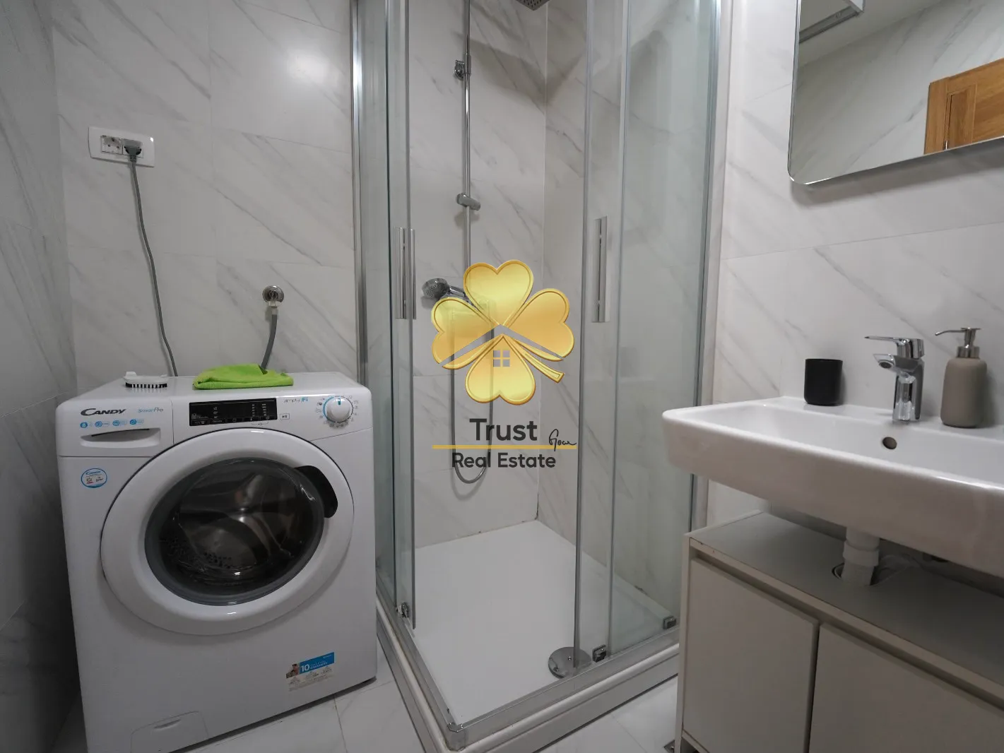 Modernly equipped bathroom with a shower cabin, washbasin, and washing machine.