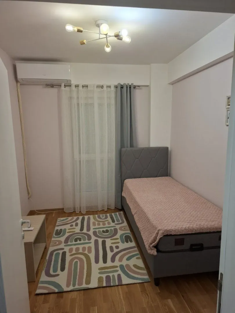 Manja spavaća soba sa krevetom na rasklapanje i šarenim tepihom.