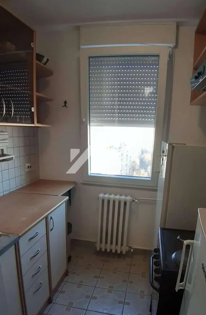 Smaller kitchen with a window, cabinetry, and a refrigerator.