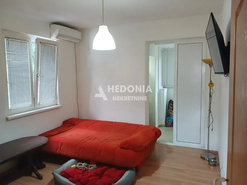 Manja spavaća soba sa crvenim krevetom i klima uređajem.