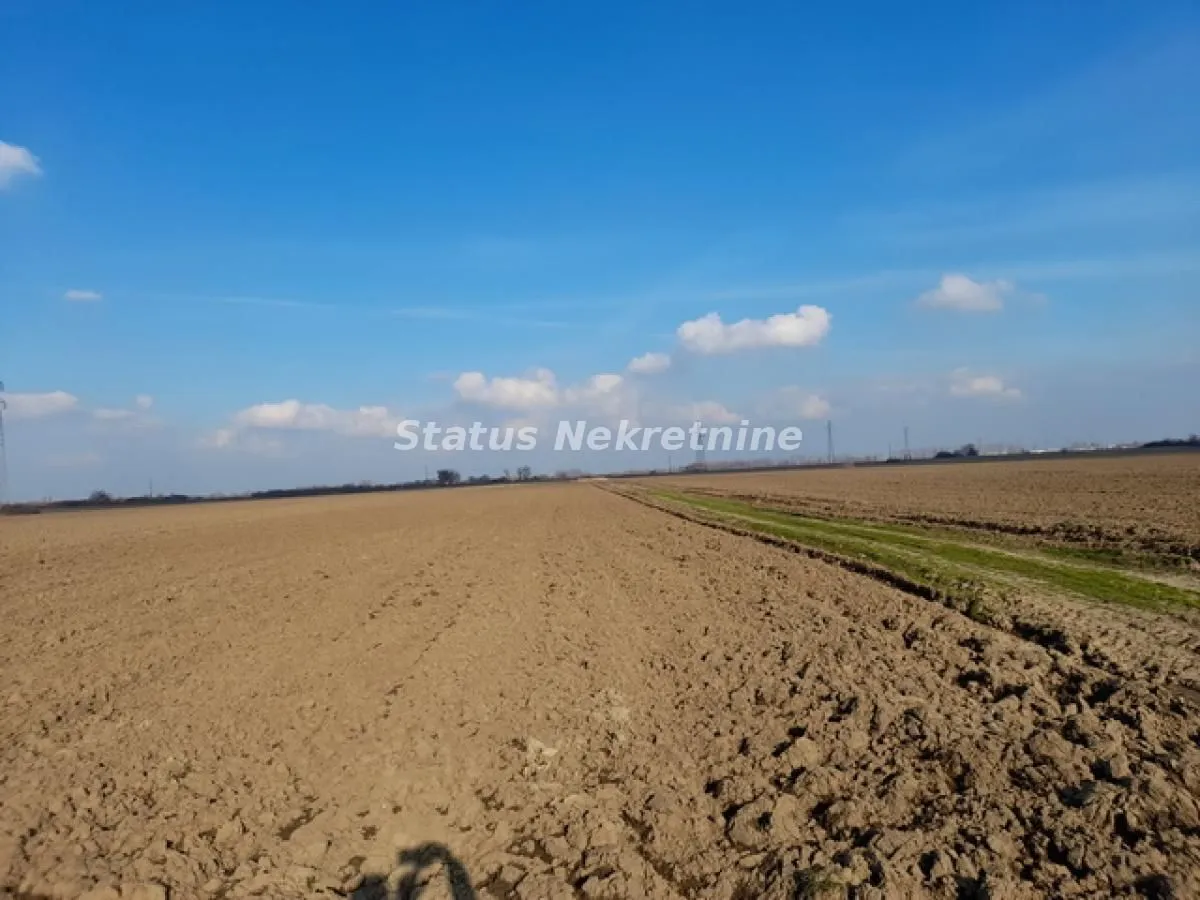 Pogled na prostrano poljoprivredno zemljište pod vedrim nebom.