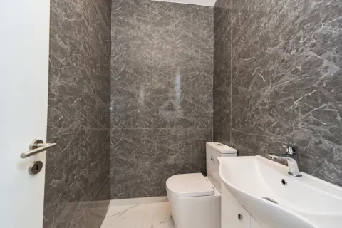 Small bathroom tiled in grey marble with a built-in toilet and washbasin. - image 4