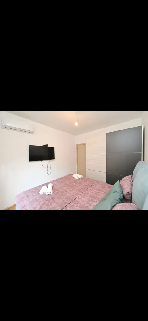 Furnished bedroom with a double bed, wardrobe, and TV.