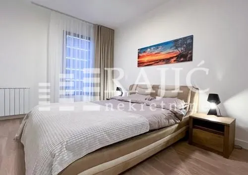 Furnished bedroom with a double bed, nightstand, and a window with curtains.