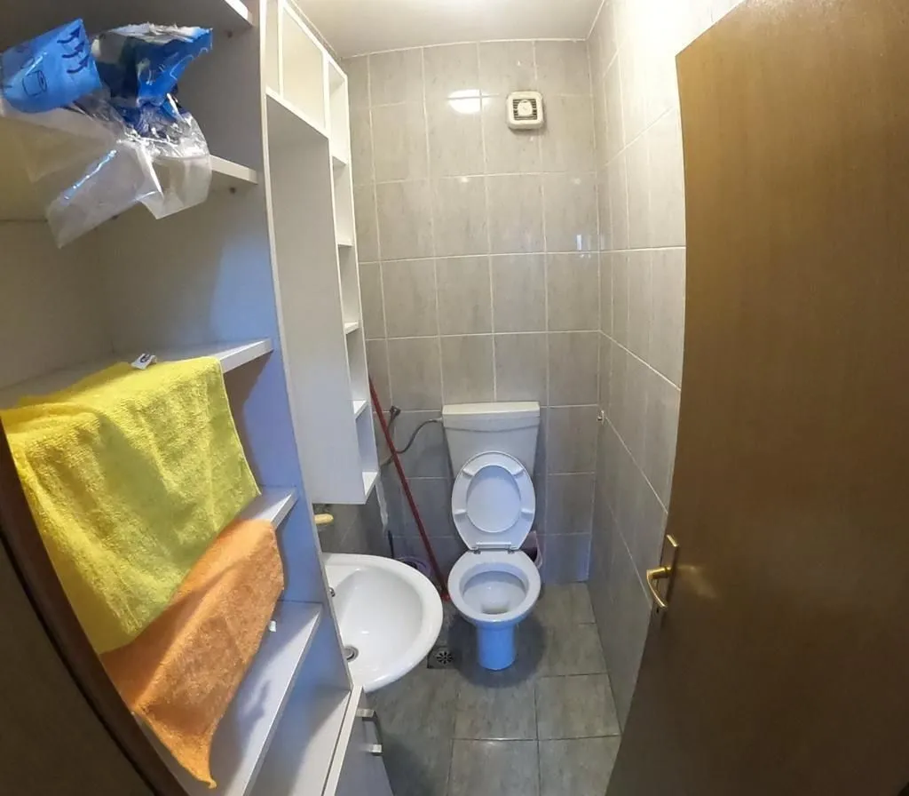Malo kupatilo sa toaletom, umivaonikom i policama za odlaganje.