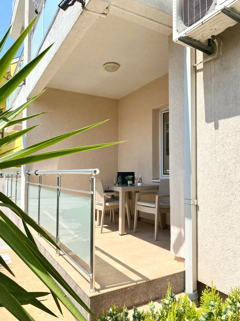 Covered terrace with a table, chairs, and metal railing.