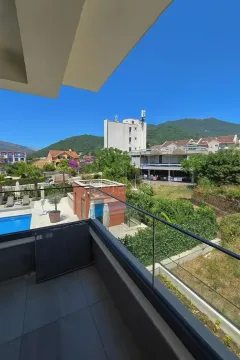 Pogled sa terase na bazen i okolne zgrade sa brdima u pozadini. - image 6