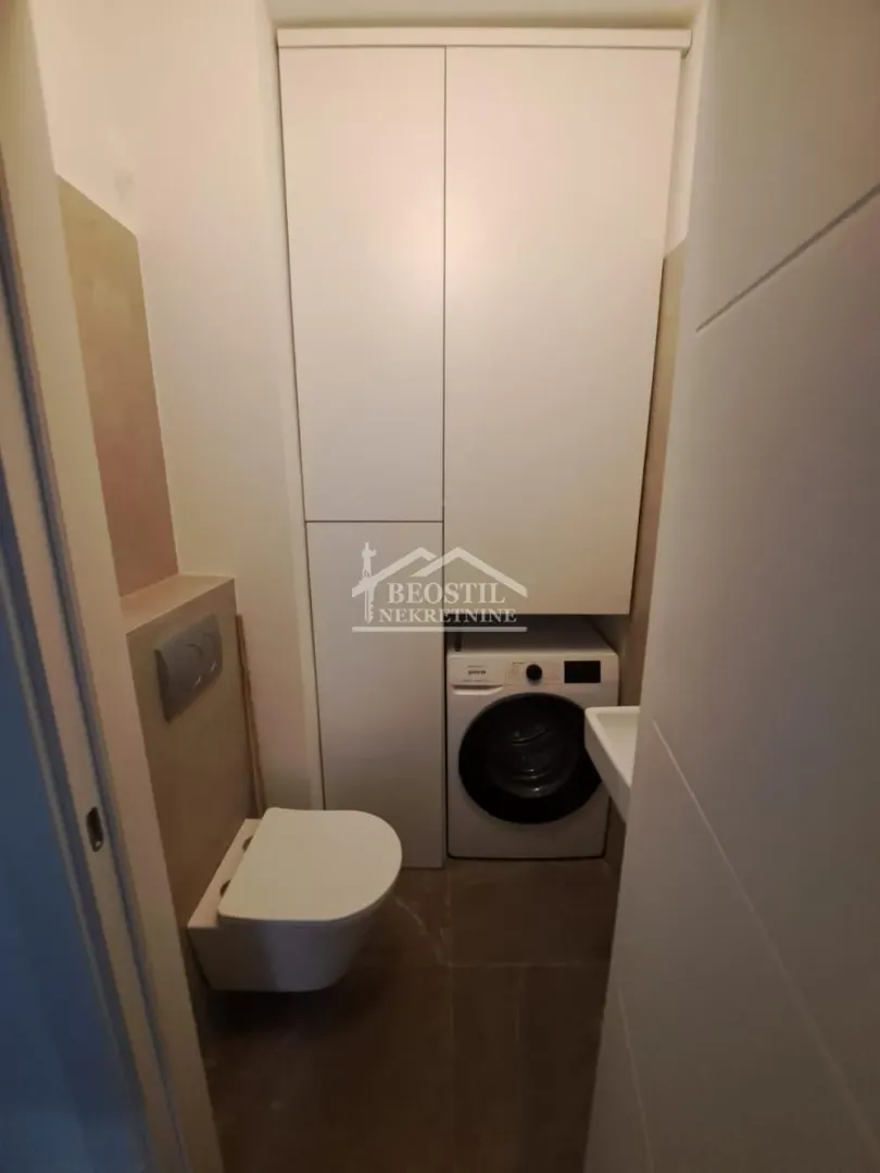 Kupatilo sa toaletom, ugradnim ormarom i veš mašinom.
