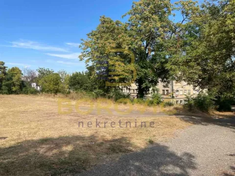 Pogled na plac sa travnatom površinom i visokim drvećem. - image 2
