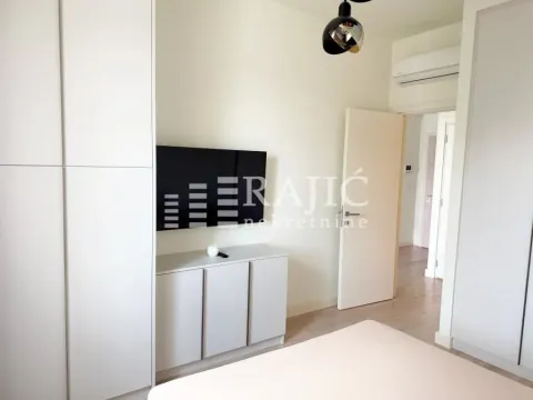 Bright bedroom with built-in wardrobes and a television. - image 7
