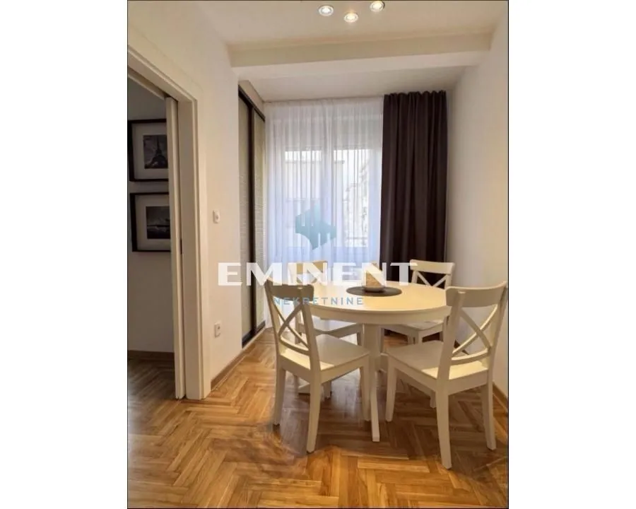 Dining area with a white table and chairs next to the window with curtains.