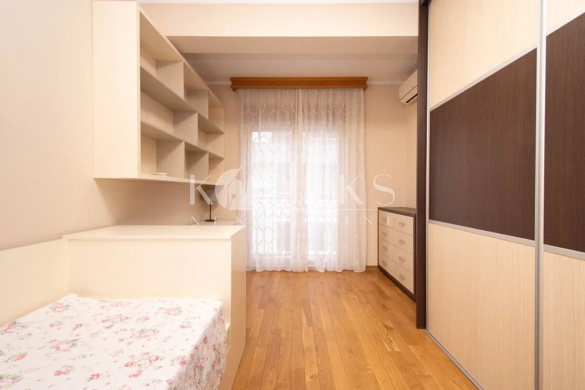 Small bedroom with a bed, a large wardrobe, shelving units, and a desk.