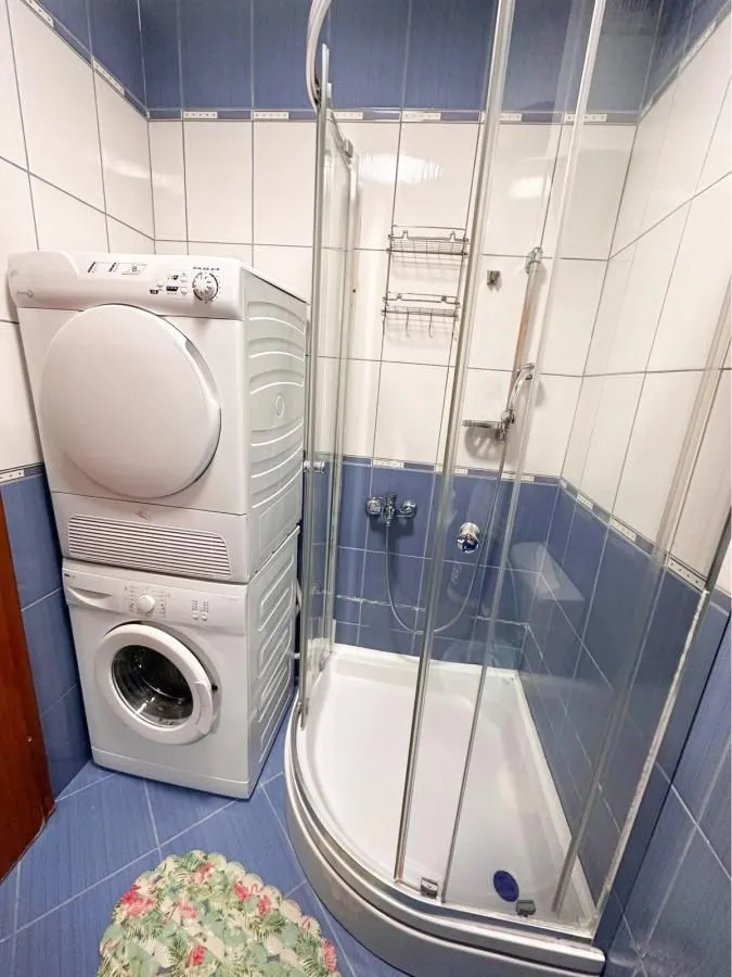 Kupatilo sa tuš kabinom i mašinama za pranje i sušenje veša.