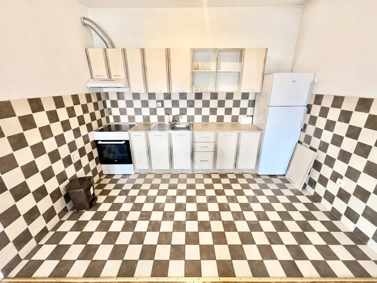 Kitchen equipped with white cabinets and black and white ceramic tiles on the wall and floor.