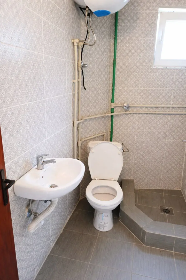 Manje kupatilo sa WC šoljom, umivaonikom i tuš kutkom.