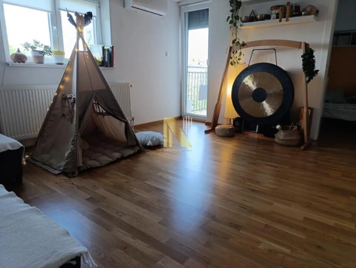 Living room with wooden flooring, a children's tent, and a musical gong.