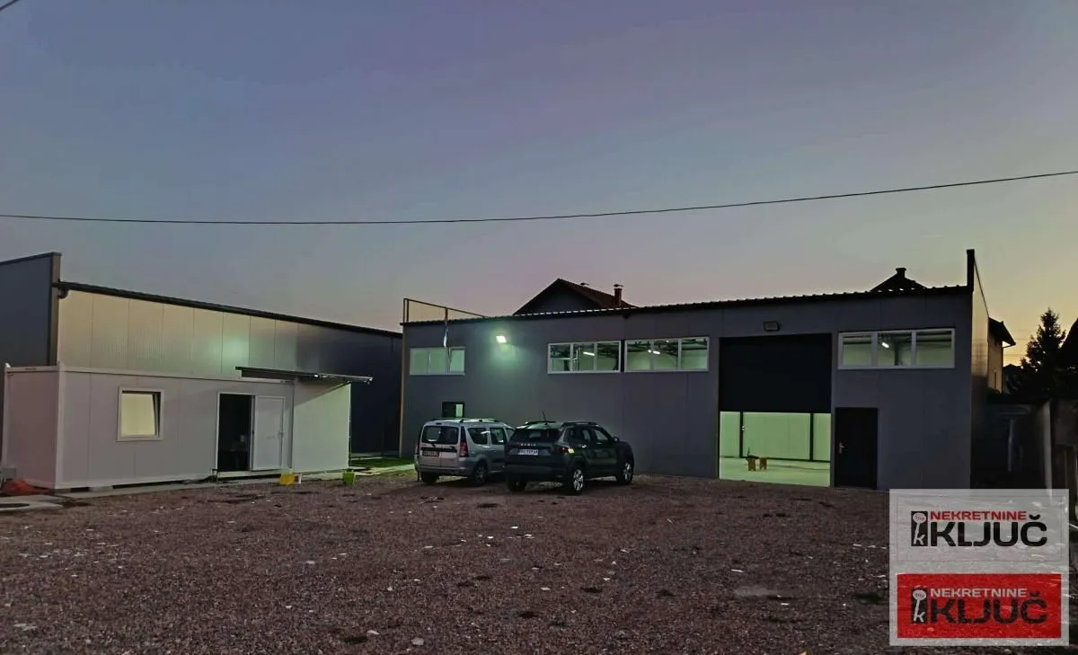 Exterior view of an industrial building with parking at dusk.