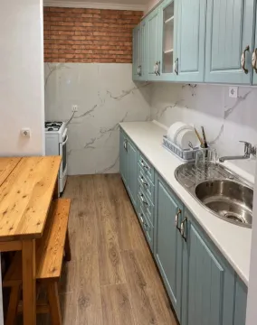 Moderna kuhinja sa plavim elementima i trpezarijskim stolom. - image 2