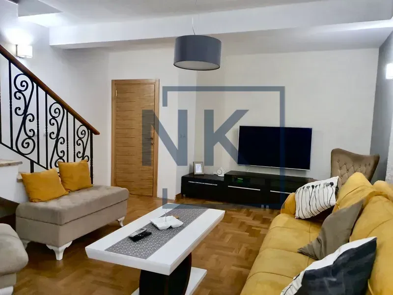 Living room with sofa set, television, and stairs.