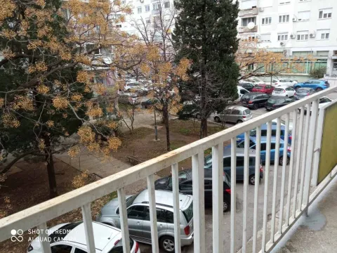 View from the balcony overlooking a park and parking area. - image 17