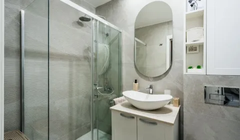 Modern bathroom equipped with a shower cabin, washbasin, and mirror. - image 9