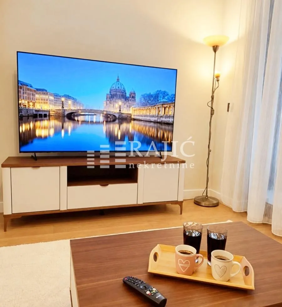 Dnevna soba sa garniturom, televizorom i stočićem.