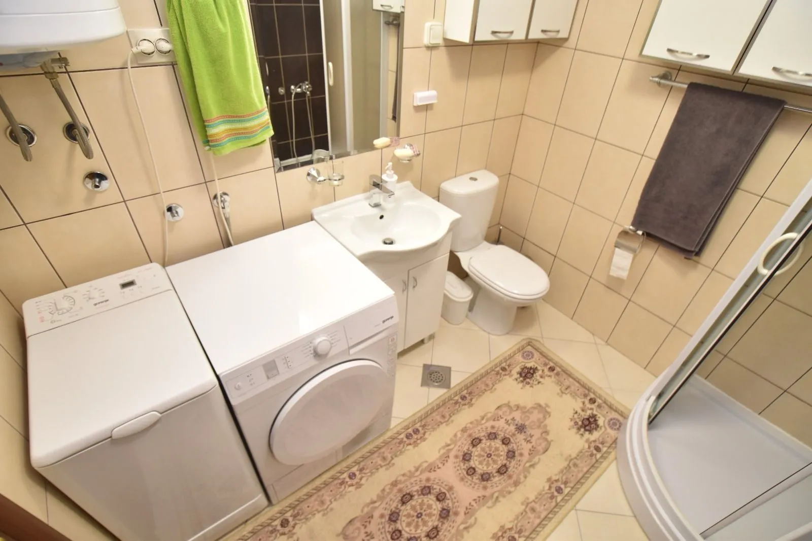 Funkcionalno kupatilo sa veš mašinom, mašinom za sušenje i tuš kabinom.