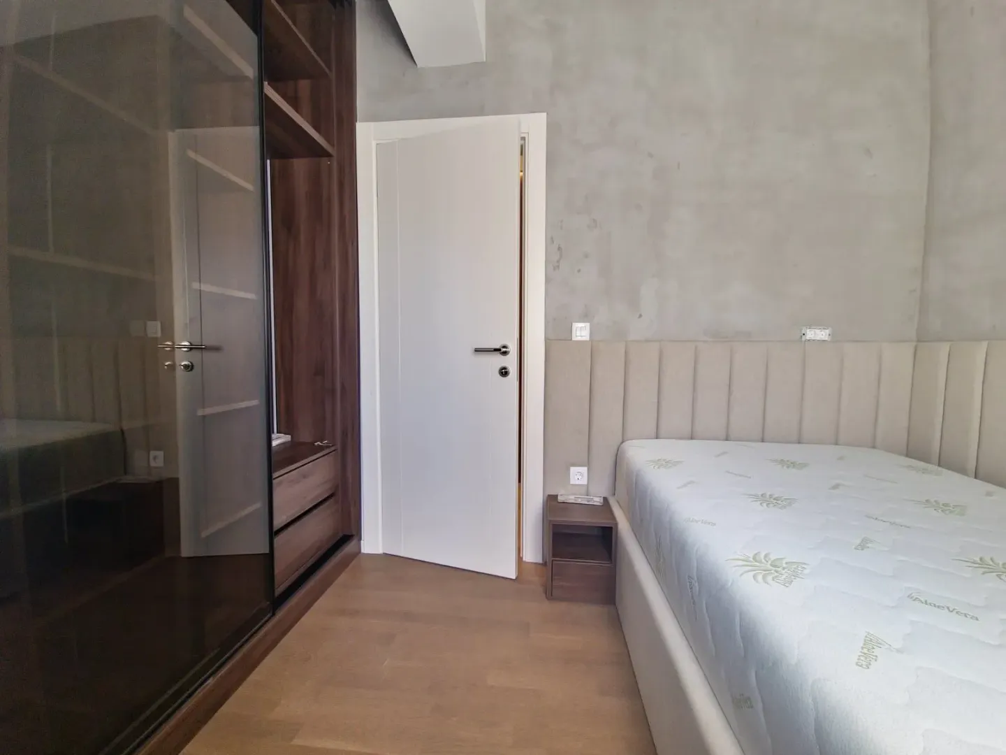Bedroom with a double bed, fitted wardrobe, and a white door.