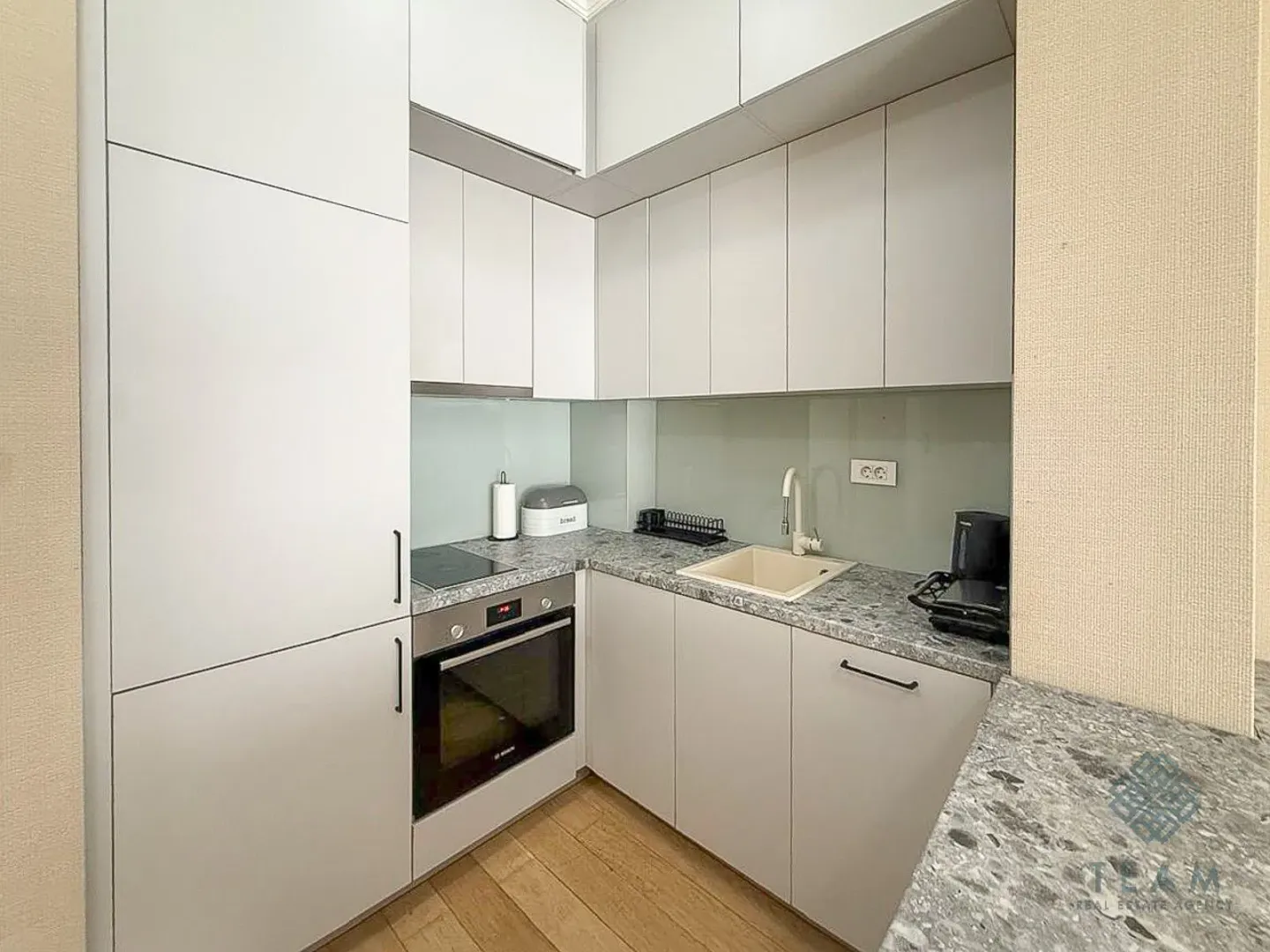 Modern kitchen with white cabinets and a built-in oven.