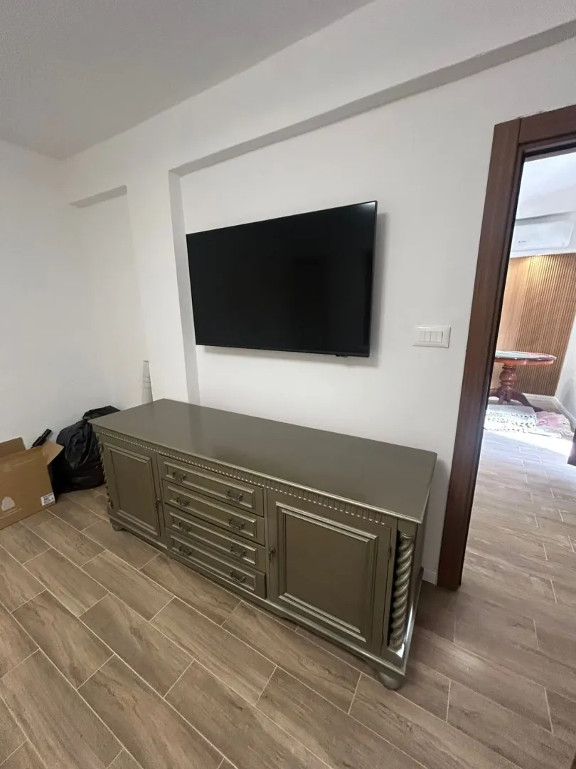Dnevna soba sa TV komodom i televizorom na zidu.