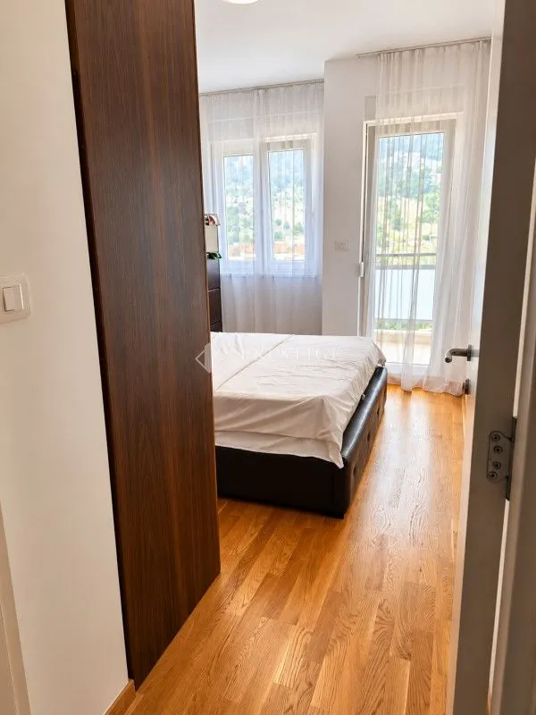 Bedroom with a double bed, wooden floor, and balcony access.