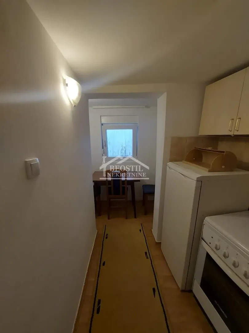Manja kuhinja sa šporetom, frižiderom i prolazom ka trpezariji.
