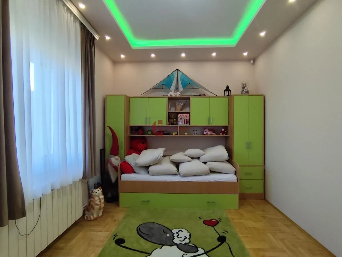 Children's bedroom with a bed, green furniture, and a drop ceiling with lighting.