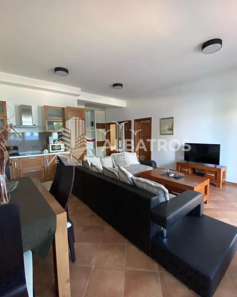 Living room with a sofa set, dining area, and kitchen in the background.