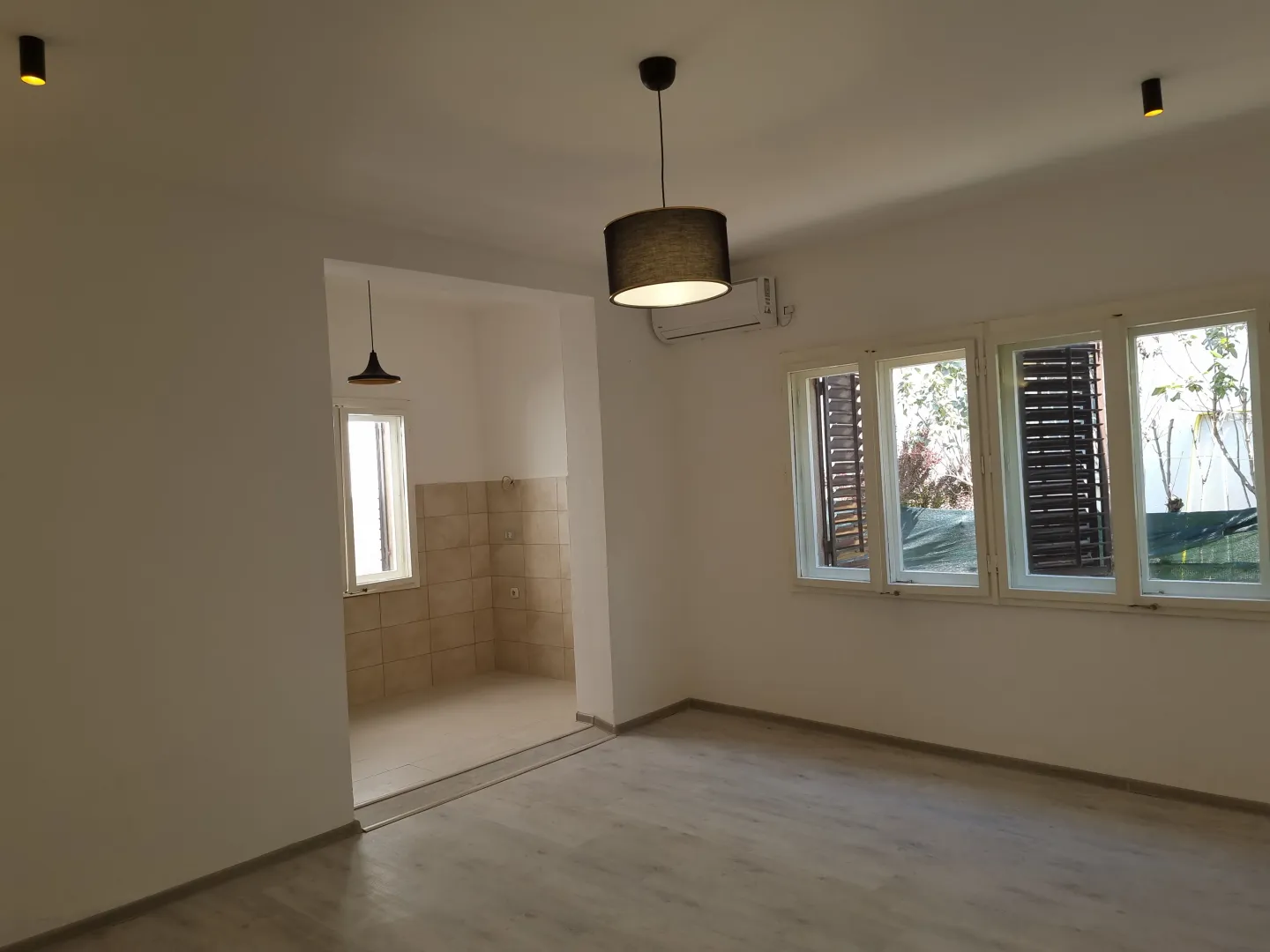 Empty living room with light walls and laminate flooring.