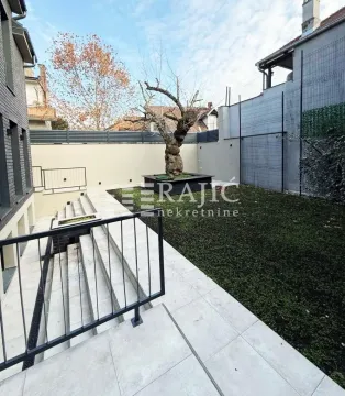 Uređeno dvorište sa popločanim stepeništem i travnatom površinom ispred zgrade. - image 8
