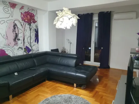Svijetla dnevna soba sa velikom crnom kožnom ugaonom garniturom i očuvanim parketom. - image 7